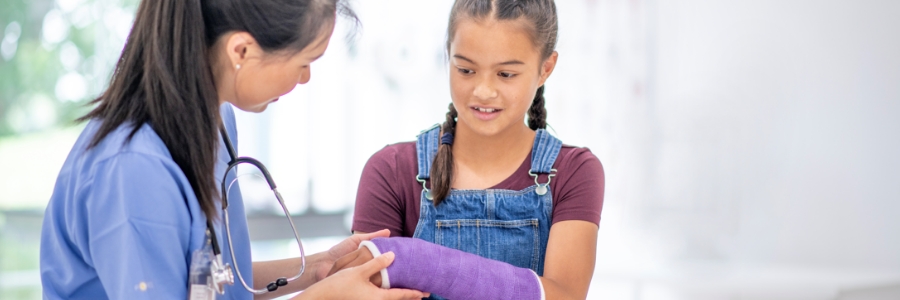 A doctor helping a child with a cast on her arm