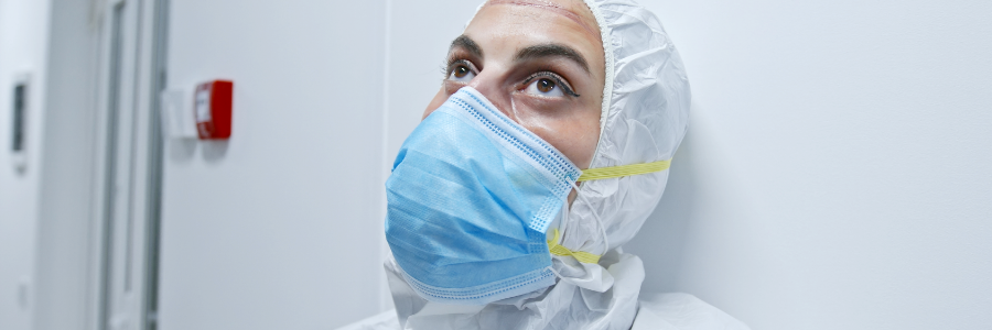 Une médecin à l’air fatigué portant un équipement de protection individuelle complet