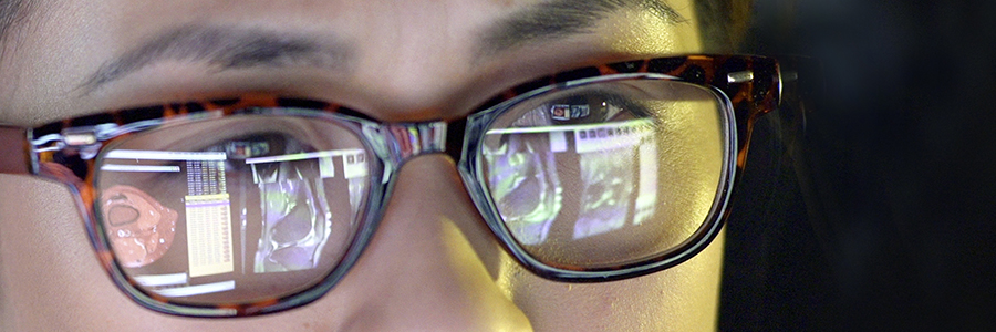 Close-up of a young woman intently studying computer screens displaying medical information