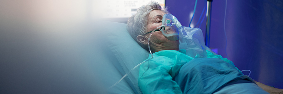 Female patient in bed with oxygen mask.