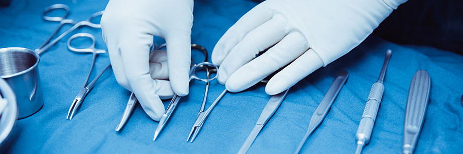 Close-up of scrub nurse taking medical instruments