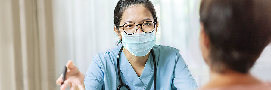 Female doctor wearing face mask, in discussion with a patient