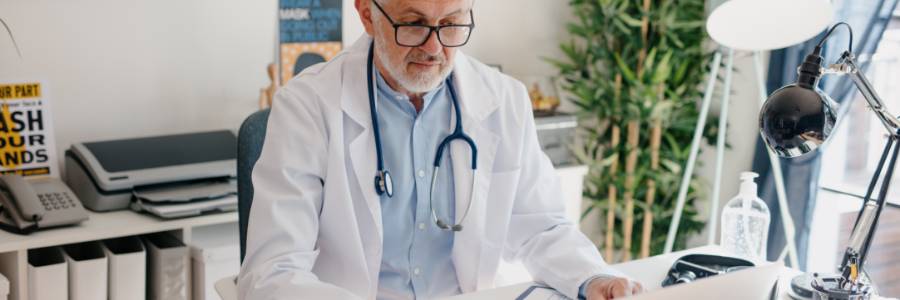 Older male doctor viewing laptop computer