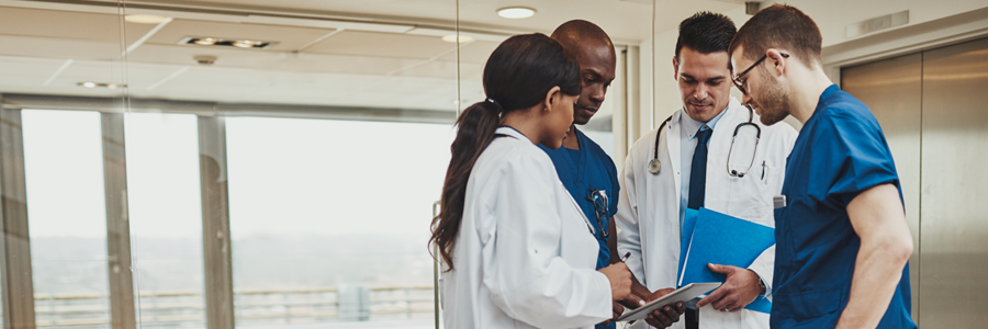 A small group of healthcare professionals meets in a hallway.