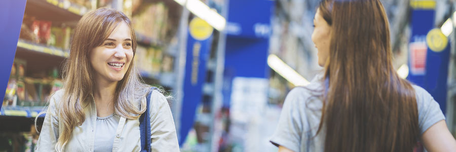 Two women having a conversation at a grocery store.