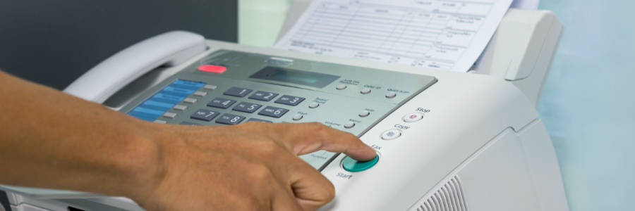 Image of a person’s hand operating a fax machine.