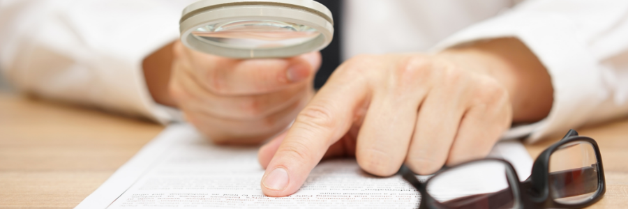 Une personne lisant un document papier à l’aide d’une loupe.