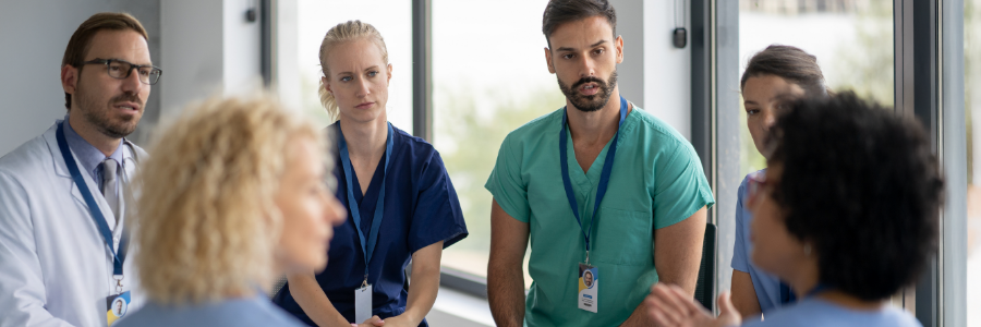 A group of physicians gathered in a peer support session in a hospital setting.