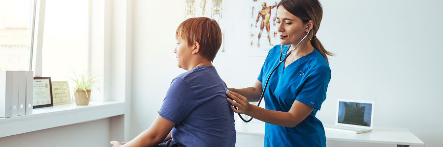 Médecin qui ausculte le dos d’un jeune patient avec un stéthoscope dans une salle d’examen