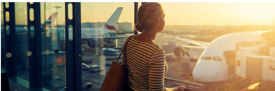 Femme qui observe les avions sur le tarmac à travers la fenêtre d’un aéroport