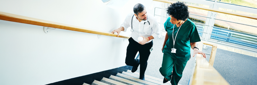 Two doctors on a staircase having conversation.