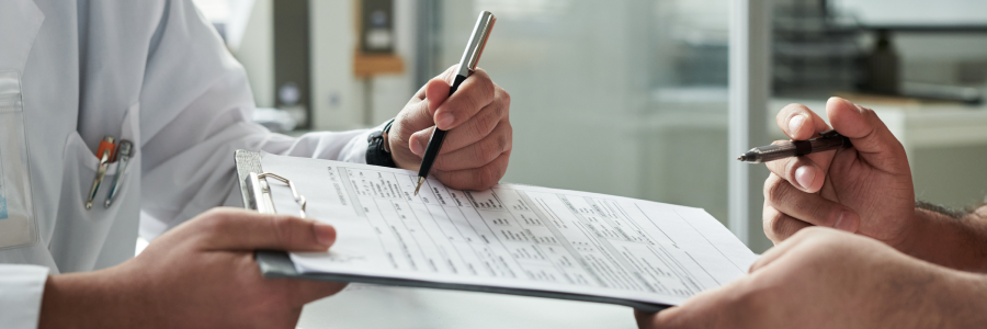 Médecin et une autre personne qui tiennent un crayon et qui examinent un document sur une planche à pince