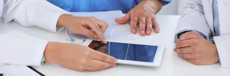 Médecins en train d’examiner un dossier médical électronique sur une tablette.