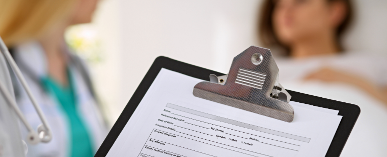 Healthcare professional filling out chart with patient in background