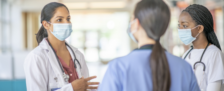 Female physician speaks with colleagues.