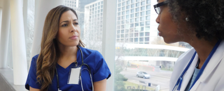 Female physician speaks with colleague.