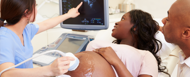 Pregnant patient and their partner reviewing an ultrasound with a sonographer