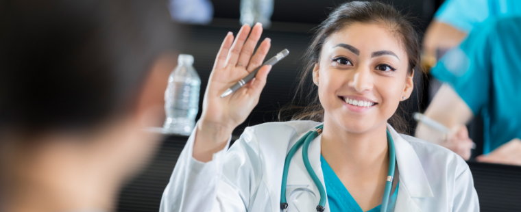 Jeune médecin qui lève la main en souriant.