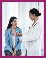 Young female physician having conversation with female patient in examining room