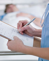 Une infirmière prend des notes dans un dossier, un patient en arrière-plan.