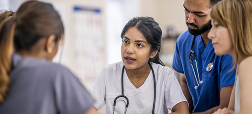 Female physician leading a team huddle with other health professionals.