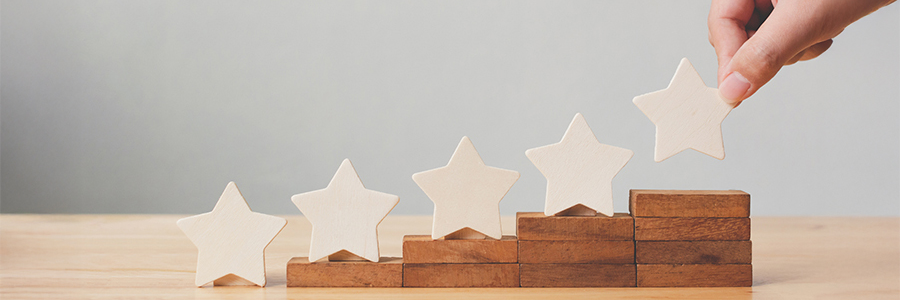 Une main dépose la 5ème étoile sur la plus haute des cinq marches illustrant la poursuite du niveau des soins le plus élevé.