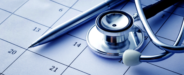 Stethoscope and pen placed on top of a calendar.