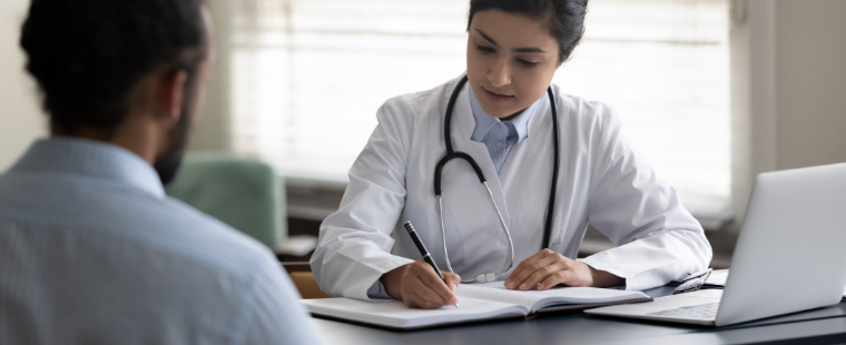 Female physician taking notes during patient consultation.