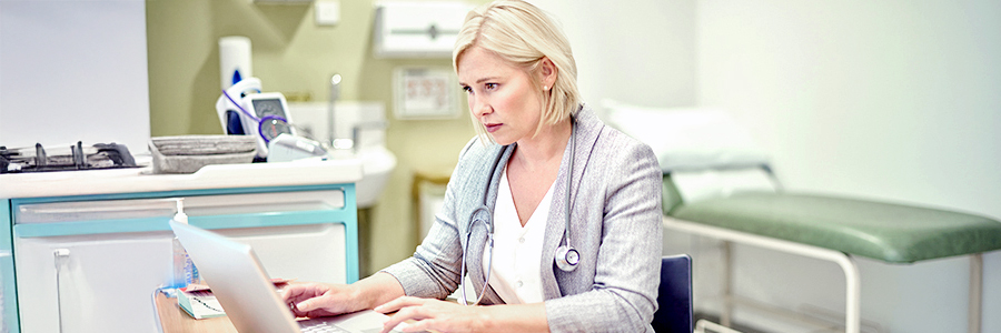 Une médecin travaille sur un ordinateur portable dans son cabinet.