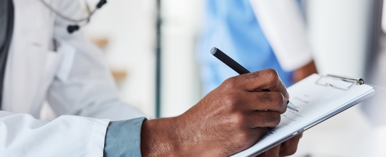 Physician writing on a clipboard.