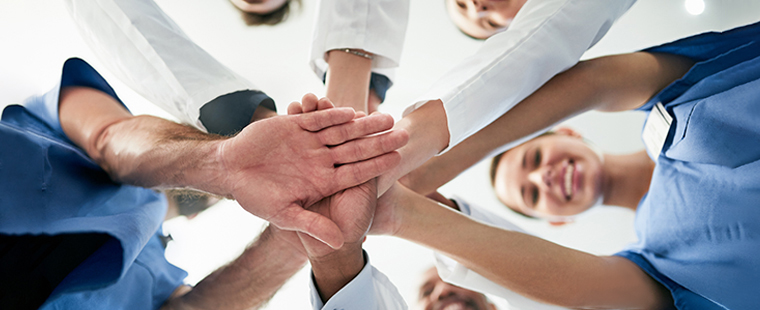 A diverse team of doctors joining their hands together in unity.