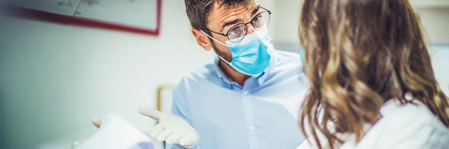 Deux collègues médecins sont en désaccord au sujet des résultats d’analyse. Ils portent un masque et des gants pour se protéger.