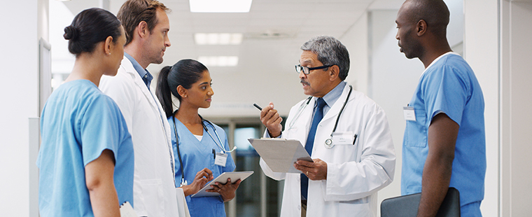 A group of medical practitioners having a discussion in a hospital hallway.