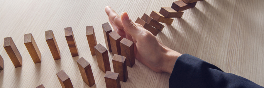 Une main empêchant des blocs de bois de renverser d’autres formations de blocs.