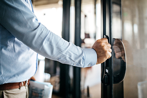 Male doctor with hand on door handle leaving office.