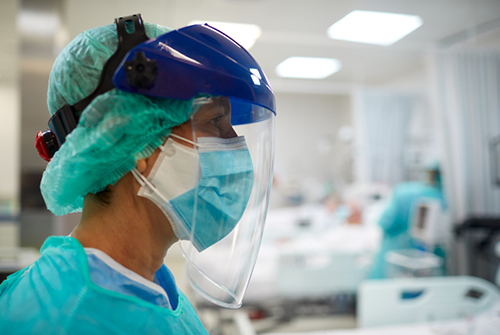 close-up of physician wearing a facemask, face shield, and other PPE in the ICU.