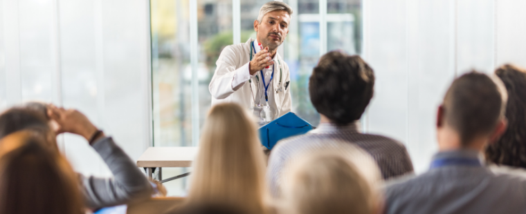 Male physician-educator talking to a group of trainees.