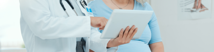 A physician shares information from a tablet with a pregnant patient