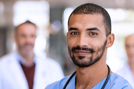 A male physician, with other physicians in the background