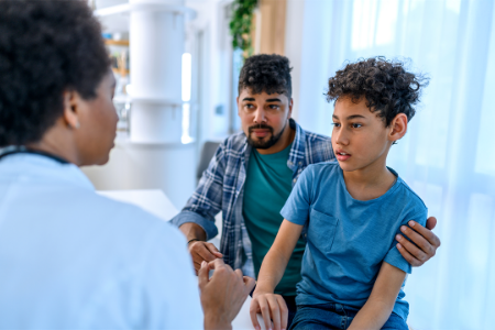 Une médecin en consultation avec un garçon et son père