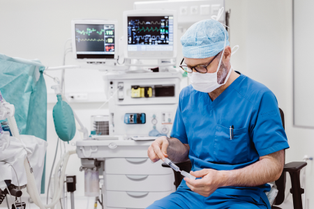 An anesthesiologist at his workstation prepares a syringe of medication