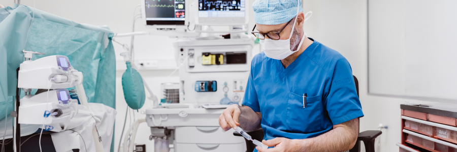 An anesthesiologist at his workstation prepares a syringe of medication