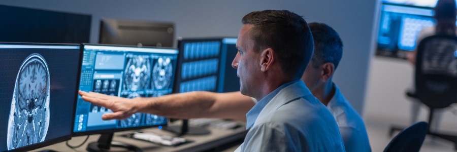Two diagnostic radiologists review imaging on computer monitors