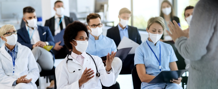 A group of medical professionals ask questions while wearing medical face masks